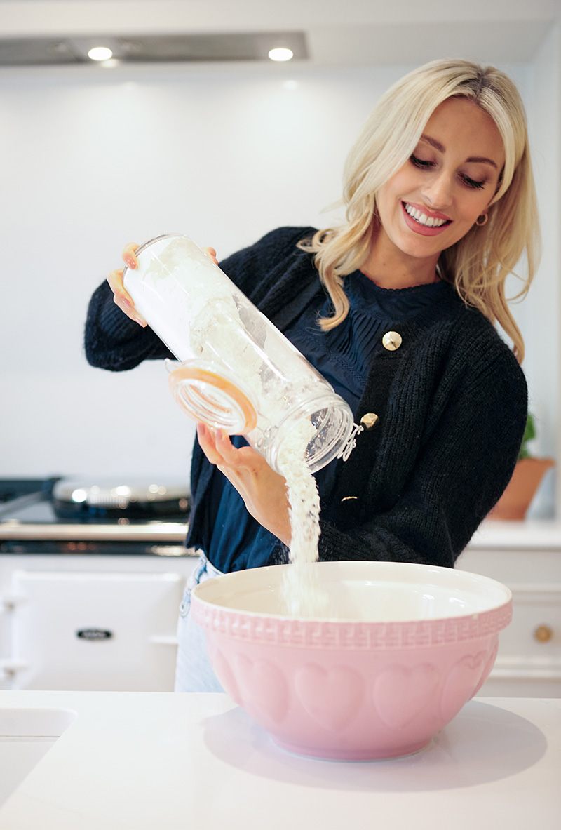 Chloe Chilton pouring flour alongside AGA R7 160 in white