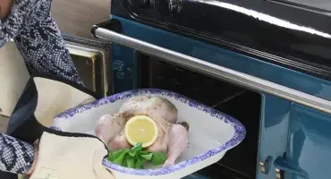 A chicken being placed in to the AGA oven