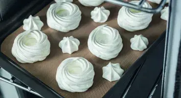 Meringues on baking tray going into oven