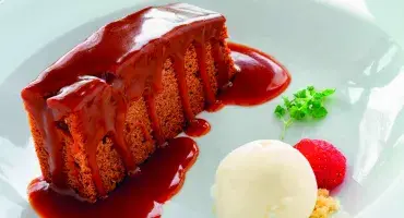 Slice of Sticky Toffee Traybake with ice cream and strawberry