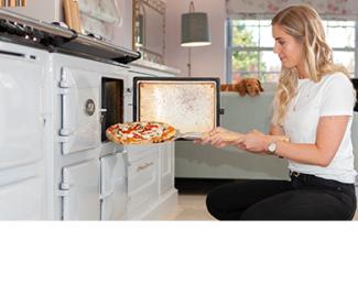 Lady putting pizza in to the AGA Cooker
