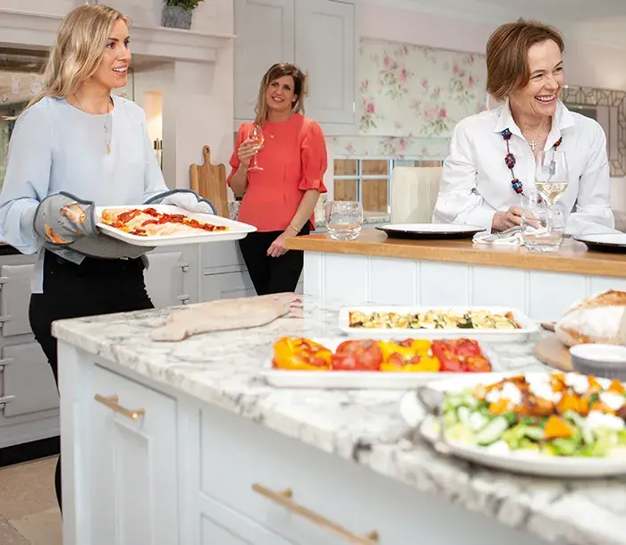 Three ladies in kitchen cooking with an AGA