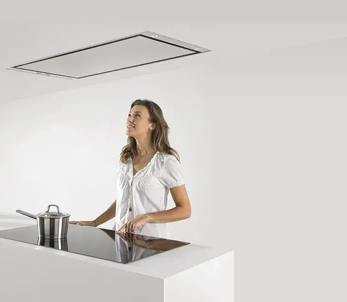 Lady looking up at Novy ceiling extraction hood in white kitchen